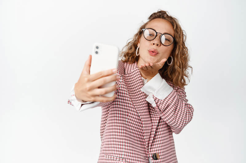Девушка в очках делает селфи на смартфон